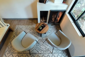 A modern living room with a fireplace, two armchairs, a coffee table, and a patterned rug.