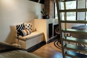 A modern living room with a sofa, a fireplace, and a view of the outdoors.