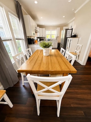 Una cocina moderna con armarios blancos, una mesa de comedor de madera y una planta en maceta.
