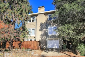 Une maison à deux étages avec un garage, une clôture en bois et un mur en pierre.