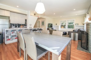 Une cuisine moderne avec un coin repas, comprenant une grande table, des chaises et un luminaire suspendu.