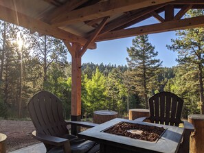 Eine Terrassenholzdiele mit zwei Adirondack-Stühlen und einer Feuerstelle.