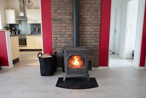 A modern kitchen with a built-in wood stove, a brick wall, and a red accent wall. - New Listing (Gaillac)