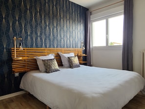 A bedroom with a wooden headboard, two pillows, a white bedspread, and a window with curtains. - New Listing (Gaillac)