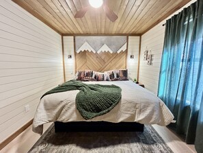 Une chambre à coucher avec un lit, un plafond en bois et une tête de lit sur le thème de la montagne.
