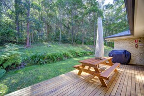 Eine Holzterrasse mit Picknicktisch, umgeben von einem üppigen, grünen Wald.