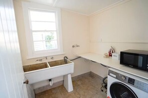 Une buanderie équipée d’un lave-linge, d’un évier et d’un four à micro-ondes.