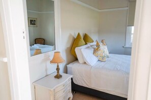 Une chambre à coucher avec un lit, une table de chevet, une lampe et un miroir.