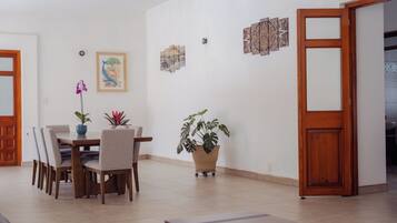 Ein Essbereich mit Tisch und Stühlen, einer Topfpflanze und einer Wand mit Kunstwerken.