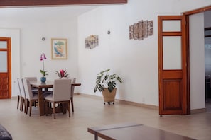 Ein Essbereich mit Tisch und Stühlen, einer Topfpflanze und einer Wand mit Kunstwerken.