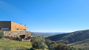 Ein modernes Gebäude mit einer Steinfassade, einem flachen Dach und Blick auf sanfte Hügel.