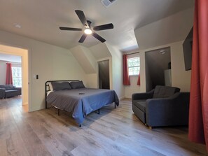 Un dormitorio con cama, escritorio, silla y ventilador de techo.
