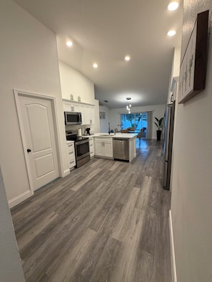 A modern kitchen with white cabinetry, a central island, and a view into the dining area. - 3-bedroom house in nice Land O' Lakes with cool AC (Land O' Lakes)