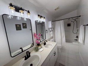 Un baño moderno con dos lavabos, un espejo grande y una zona de ducha.