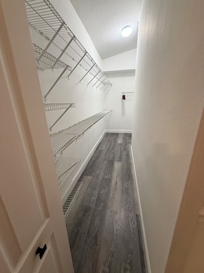 A narrow hallway with a wooden floor and metal shelving units. - 3-bedroom house in nice Land O' Lakes with cool AC (Land O' Lakes)