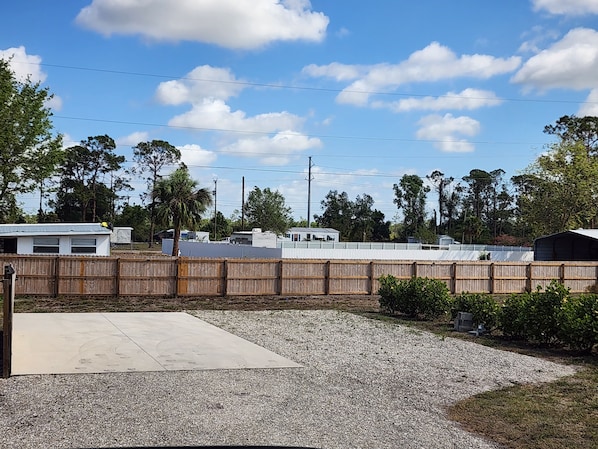A fenced outdoor area with a gravel surface, a concrete slab, and a row of mobile homes in the background. - Beautiful campground in nice North Fort Myers location Behind my house (North Fort Myers)