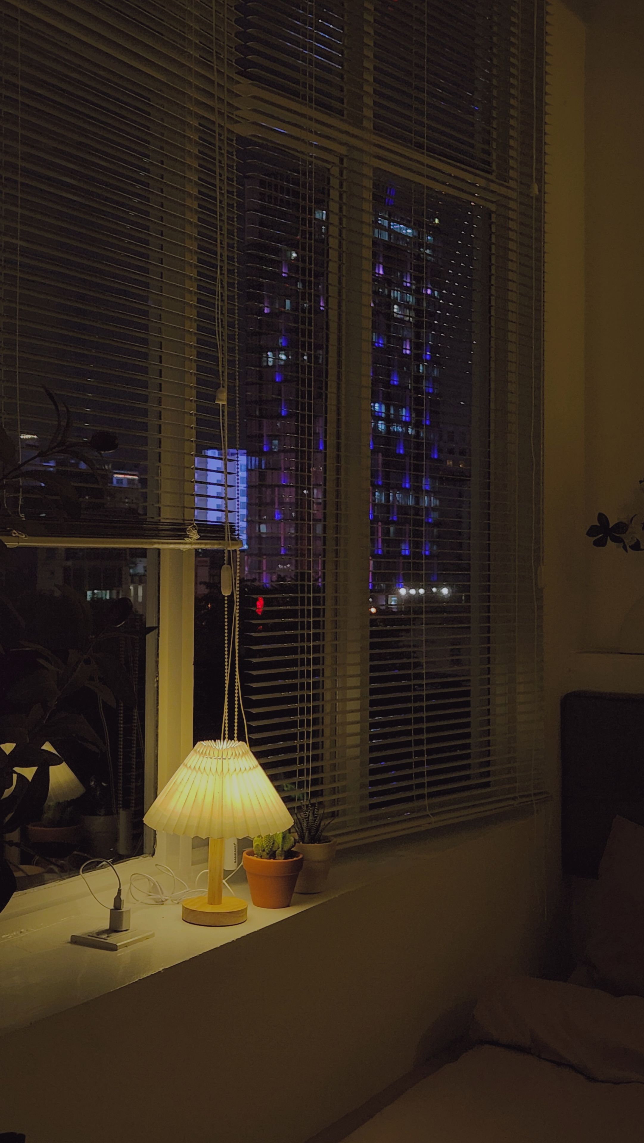 A room with a window overlooking a cityscape at night.