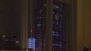 A room with a window overlooking a cityscape at night.