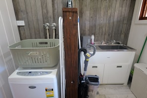 Ein Waschbereich mit Waschmaschine, Trockner, einem Wäscheständer aus Holz und einem Waschbecken.