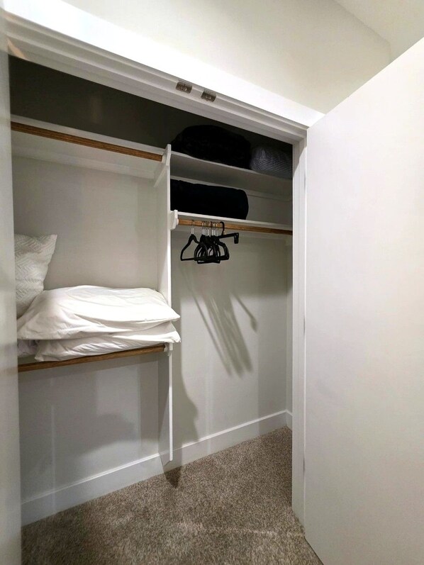 Ein begehbarer Kleiderschrank mit Bett, Ablagefläche und Kleiderstange.