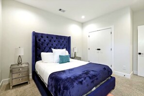 Une chambre à coucher avec un grand lit, deux tables de chevet, une armoire et une porte.