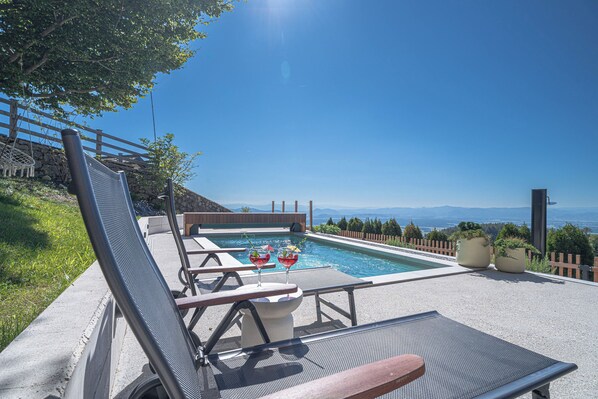 Area piscina con lettini, una piccola piscina e vista sulle montagne.