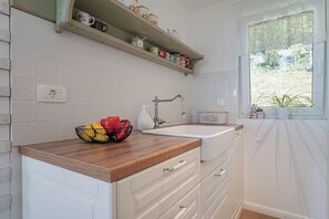 Una cucina con un piano di lavoro in legno, un lavello e una finestra vista verde.