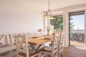 Zona pranzo con tavolo in legno, sedie bianche e lampadario.
