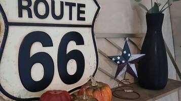 A Route 66 sign with decorative pumpkins and a star ornament on a shelf.
