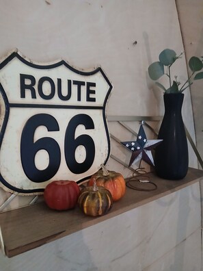 Een Route 66 bord met decoratieve pompoenen en een ster-ornament op een plank.