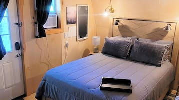 Quarto com cama, abajures, ventoinha no teto e janela com cortinas.