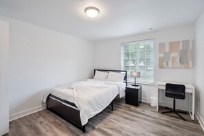 Een slaapkamer met een bed, een bureau en een stoel.