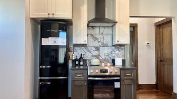 A compact kitchen with a black refrigerator, a stove, and a microwave.