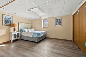 Un dormitorio con cama, mesita de noche, lámpara y dos cuadros enmarcados con motivos florales.