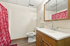 Un baño con inodoro, lavamanos, espejo y cortina de ducha.