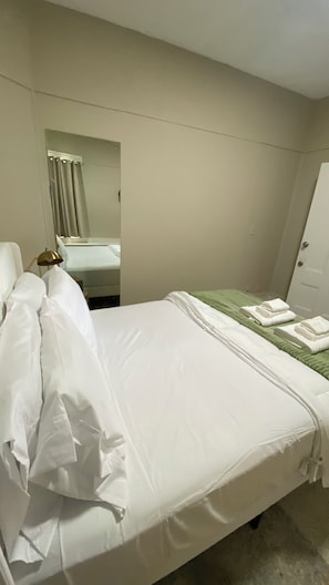 Una habitación de hotel con una cama, un espejo, una lámpara de noche y una puerta.