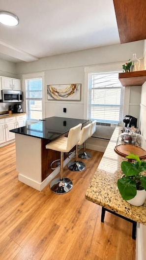 Una cocina moderna con una isla central, taburetes de bar y una planta en maceta.
