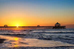 A pier extending into the sea with a sunset in the background. - Oak & Ocean Retreat - an iTrip Charleston Beaches Home (Kiawah Island)