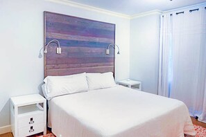 Une chambre à coucher avec un lit, des tables de chevet et un grand tableau abstrait accroché au mur.