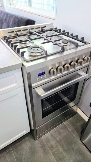 Een keuken van roestvrij staal met een gasfornuis, oven en een digitaal display.