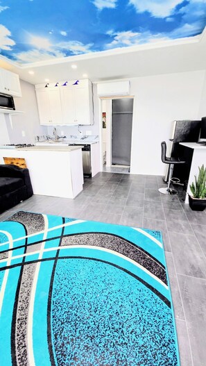 Een moderne keuken met witte kasten, een ingebouwde magnetron en een groot keukenblok met een spoelbak.