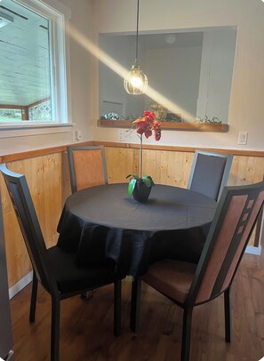 A round dining table with a black tablecloth, surrounded by wooden chairs with metal frames. - Three bedroom pet friendly home on 6 acres with a beautiful ocean view (Powell River A)