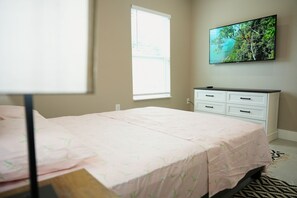 Une chambre à coucher avec un lit, une commode, une fenêtre et un tableau accroché au mur.