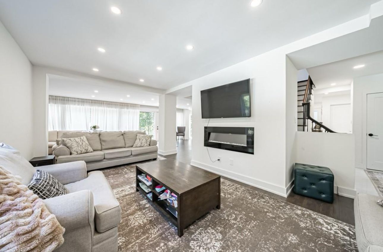 A modern living room with a sofa, coffee table, and a flat-screen TV mounted on the wall.