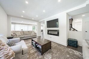 Een moderne woonkamer met een bank, salontafel en een flatscreen televisie aan de wand.