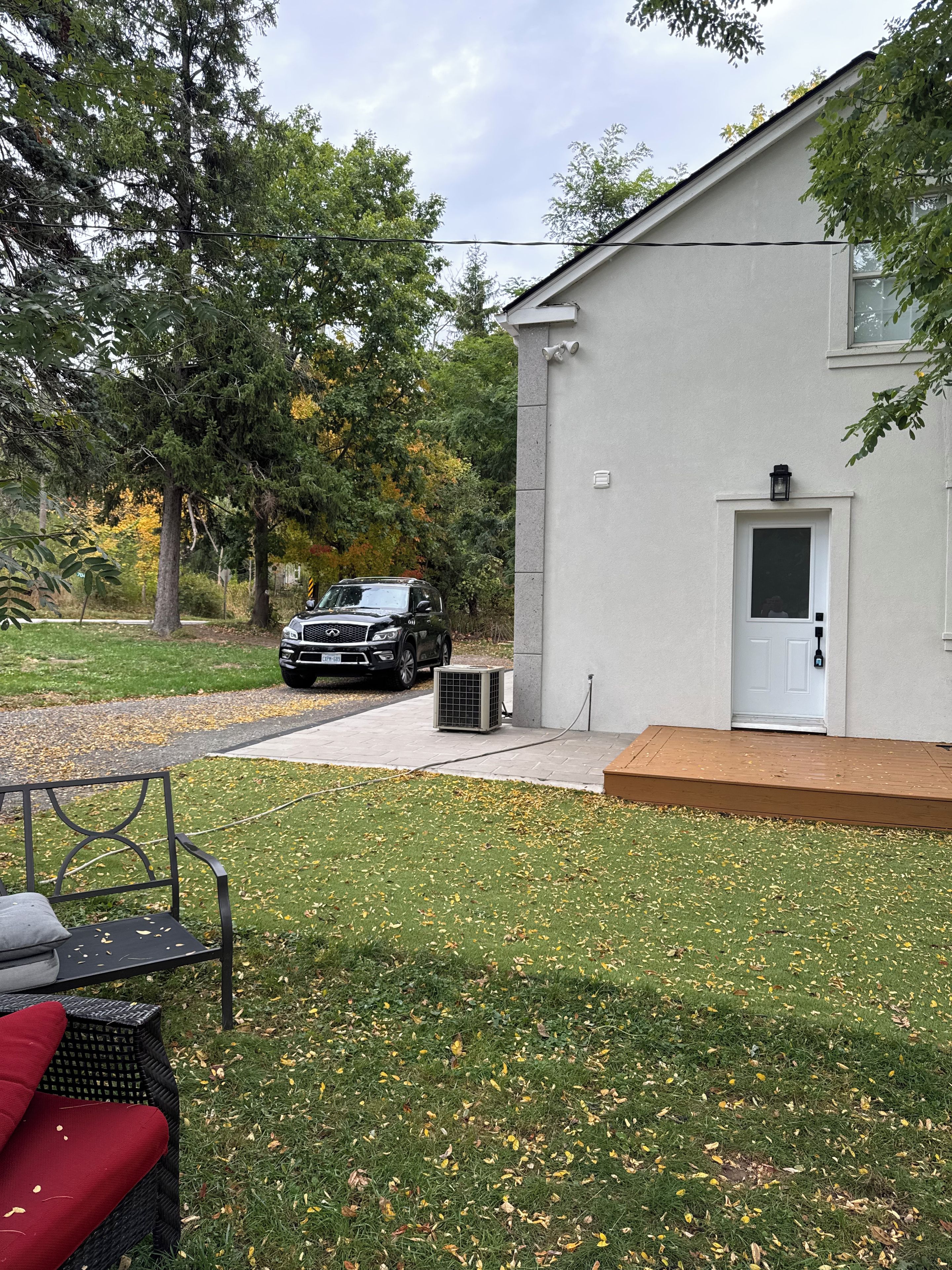 A building with a white exterior, a black vehicle parked in front, and a bench with red cushions.