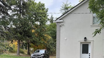 A building with a white exterior, a black vehicle parked in front, and a bench with red cushions.