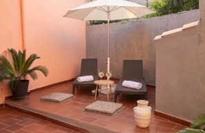 A small outdoor seating area with two lounge chairs, a table, and a potted plant. - Casa Vacanze Donna Giovanna - Cuore di Pula, vicino Nora (Pula)