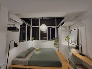 Une chambre moderne avec un lit, des lampes de chevet, un bureau et une fenêtre donnant sur un beau paysage.