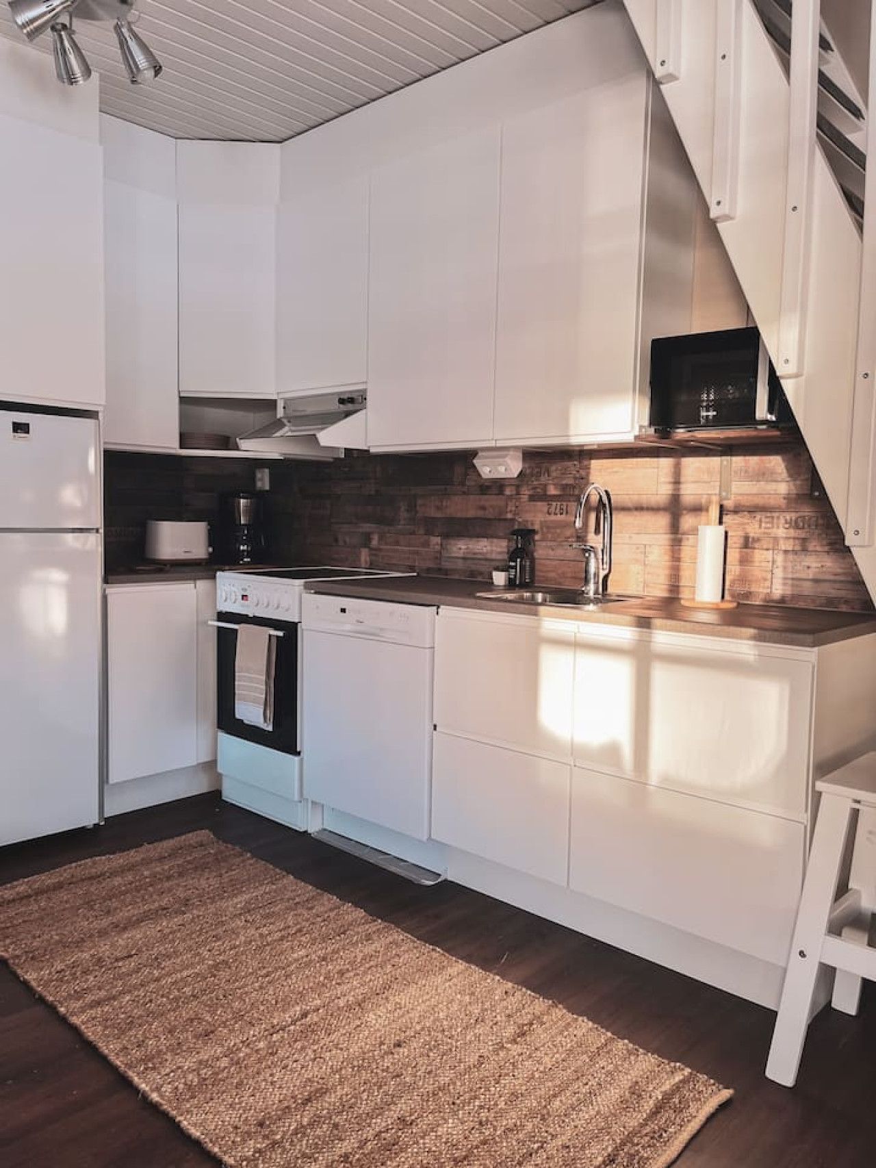 Eine moderne Küche mit weißen Schränken, einer Holzspritzschutzleiste und einem eingebauten Backofen.